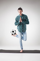 Image showing Portrait  of young man, practicing yoga with football ball