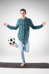 Image showing Portrait  of young man, practicing yoga with football ball