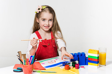 Image showing Cute little girl drawing with paint and paintbrush at home