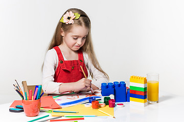 Image showing Cute little girl drawing with paint and paintbrush at home