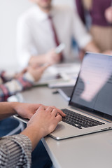 Image showing close up of business man hands typing on laptop with team on mee