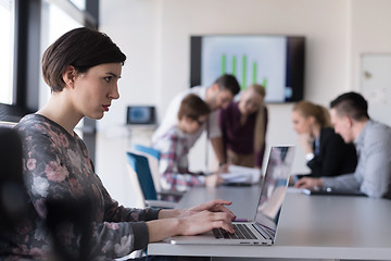 Image showing young business woman at office working on laptop with team on me