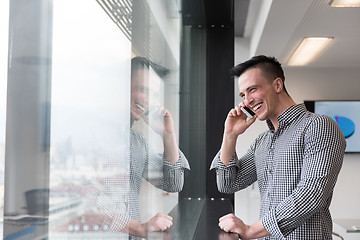 Image showing young business man speaking on  smart phone at office