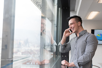 Image showing young business man speaking on  smart phone at office