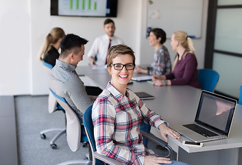 Image showing young business woman at office working on laptop with team on me