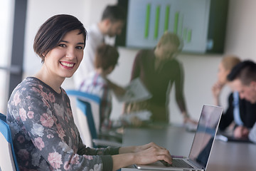 Image showing young business woman at office working on laptop with team on me