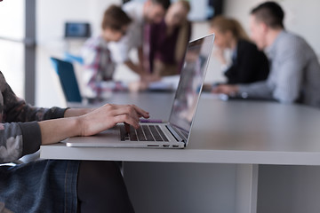 Image showing close up of business womans hand typing on laptop with team on m