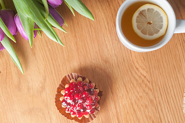 Image showing Violet tulips, cake and tea on the wood