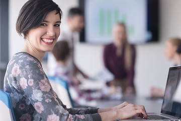 Image showing young business woman at office working on laptop with team on me