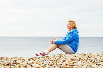 Image showing Woman sitting on the beach and looks into the distance