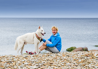 Image showing Woman  sits with a dog on the beach