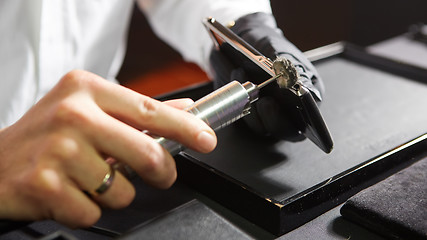 Image showing mechanical polishing of the smartphone. Male hands. 
