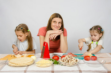 Image showing Mom sits at the kitchen table with a dreamy view of two little girls close concentration cut products