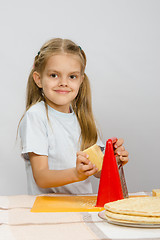 Image showing Six-year girl posing at the kitchen table with cheese and a grater in the hands of