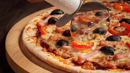 Image showing Pizza cutter wheel slicing ham pizza 