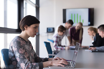 Image showing young business woman at office working on laptop with team on me