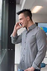 Image showing young business man speaking on  smart phone at office