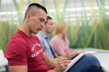 Image showing male student taking notes in classroom