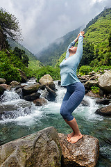Image showing Sorty fit woman doing yoga asana at waterfall