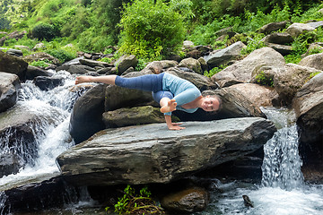 Image showing Woman doing yoga oudoors at tropical waterfall