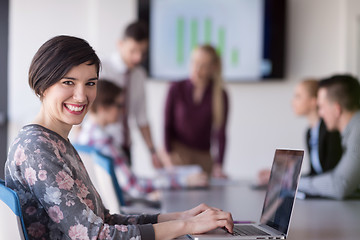 Image showing young business woman at office working on laptop with team on me