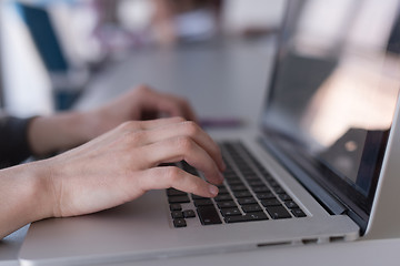 Image showing close up of business womans hand typing on laptop with team on m