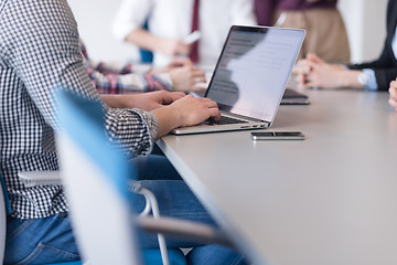 Image showing close up of business man hands typing on laptop with team on mee