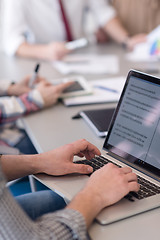 Image showing close up of business man hands typing on laptop with team on mee