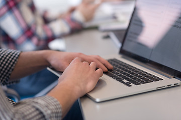 Image showing close up of business man hands typing on laptop with team on mee