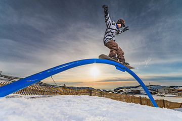 Image showing Snowboarder sliding on a rail