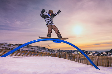 Image showing Snowboarder sliding on a rail