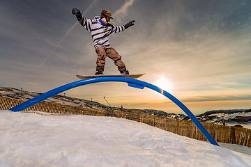 Image showing Snowboarder sliding on a rail