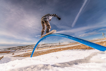 Image showing Snowboarder sliding on a rail