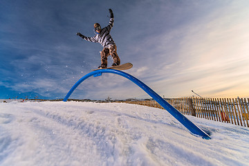 Image showing Snowboarder sliding on a rail