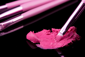 Image showing lipstick with a brush make-up on black 