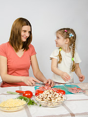 Image showing Little six year old girl joyful enthusiasm helps mum to prepare food