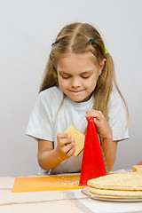 Image showing Six-year girl posing at the kitchen table with cheese and a grater in the hands of