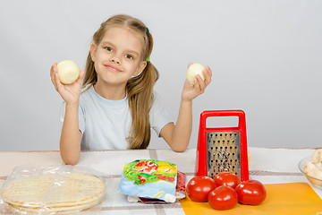 Image showing Six year old girl at the kitchen table having fun holding vegetables