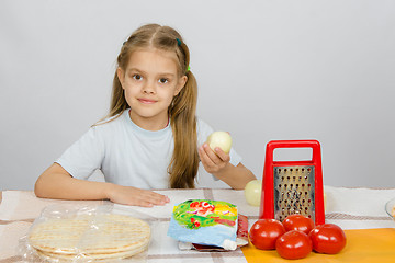Image showing Six-year girl sitting at the kitchen table in front of her are vegetables, base and other ingredients for pizza