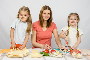 Image showing Woman with two young girls at the table prepared ingredients for pizza