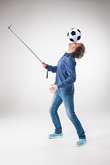 Image showing The portrait of man with ball, holding selfie stick on white background