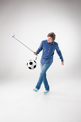 Image showing The portrait of man with ball, holding selfie stick on white background