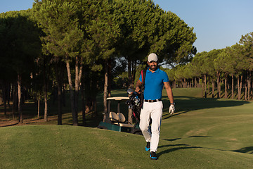 Image showing golfer  walking and carrying golf  bag