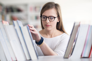 Image showing portrait of famale student selecting book to read in library