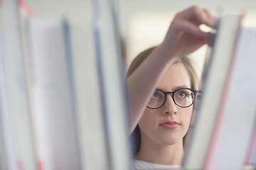 Image showing portrait of famale student selecting book to read in library