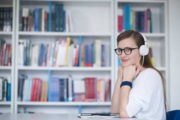 Image showing female student study in library, using tablet and searching for 