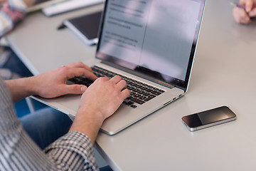 Image showing close up of business man hands typing on laptop with team on mee