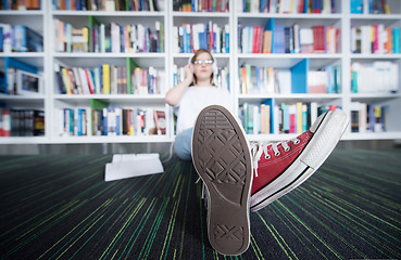 Image showing female student study in library, using tablet and searching for 