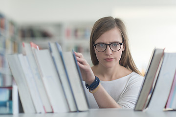 Image showing portrait of famale student selecting book to read in library