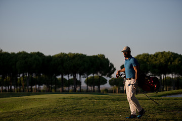 Image showing golfer  walking and carrying golf  bag at beautiful sunset